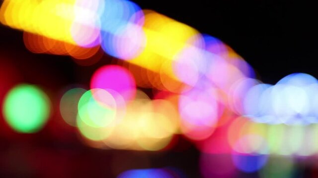 Pan shot of colorful defocused fairground lights at night