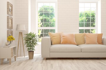 Fototapeta premium White living room with sofa and summer landscape in window. Scandinavian interior design. 3D illustration