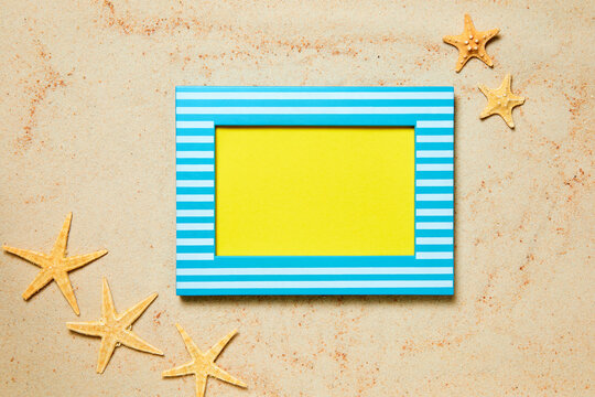 Picture frame with copy space and starfish on sand as a summer background
