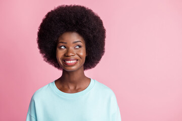 Photo of dreamy nice afro american woman look empty space smile cheerful isolated on pastel pink color background