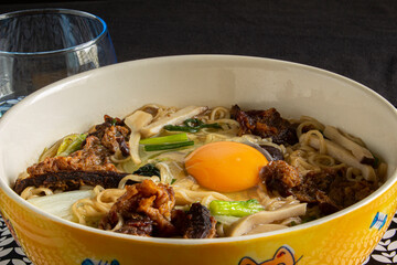 Bowl of asian noodle soup with pork, beef, vegetables and egg