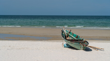 Fototapeta na wymiar A fishing boat moored on a white sandy beach by the sea with a beautiful sky.