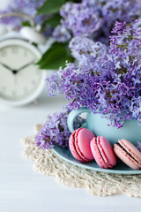 Postcard with violet lilac bouquet in a blue cup and delicious french macarons. Template for birthday card, greeting for Mother's Day, Saint Valentine's day, 8 March, Women's Day. White background