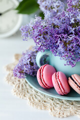 Postcard with violet lilac bouquet in a blue cup and delicious french macarons. Template for birthday card, greeting for Mother's Day, Saint Valentine's day, 8 March, Women's Day. White background