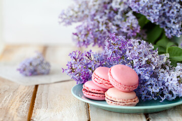 Fototapeta na wymiar Postcard with violet lilac bouquet in a blue cup and delicious french macarons. Template for birthday card, greeting for Mother's Day, Saint Valentine's day, 8 March, Women's Day. White background