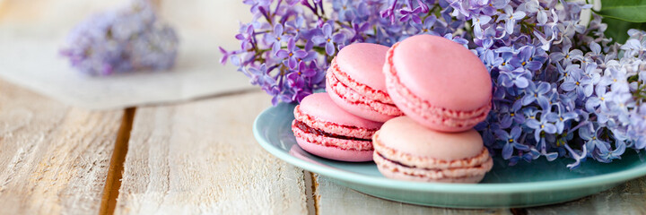 Banner with violet lilac bouquet in a blue cup and delicious french macarons. Template for birthday card, greeting for Mother's Day, Saint Valentine's day, 8 March, Women's Day. White background