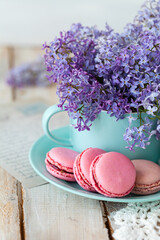 Composition with violet lilac bouquet in a blue cup and delicious french macarons. Template for birthday card, greeting for Mother's Day, Saint Valentine's day, 8 March, Women's Day. White background