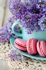 Postcard with violet lilac bouquet in a blue cup and delicious french macarons. Template for birthday card, greeting for Mother's Day, Saint Valentine's day, 8 March, Women's Day. White background