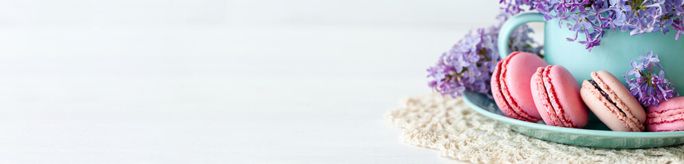 Violet lilac bouquet in a blue cup and delicious french macarons. Template for birthday card, greeting for Mother's Day, Saint Valentine's day, 8 March, Women's Day. White background banner