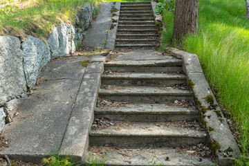 Old vintage granite stone staircase in the garden close up view. Granite dirty steps covered with lichen from time. Grey steps outdoors. Vintage grunge background.