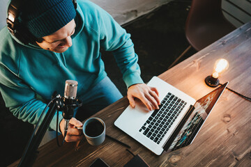 Handsome content creator streaming his live podcast using professional microphone at his broadcast studio