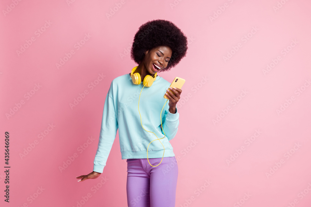 Sticker photo portrait of girl keeping cellphone wearing headphones laughing isolated on pastel pink color b