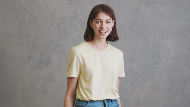 The laughing girl in a yellow t-shirt standing in the grey studio
