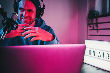 Streamer  broadcasting his live audio show at home studio using stylish cyber punk blue magenta...