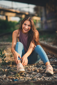 Chica sobre v&iacute;as de tren sonriendo en un atardecer