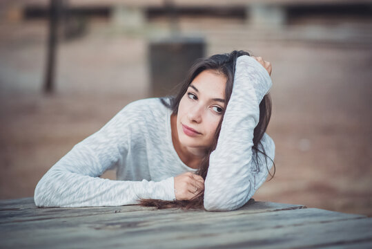 Mujer joven recostada sobre el brazo y seria