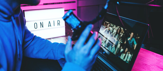 Streamer  broadcasting his live audio show at home studio using stylish cyber punk blue magenta...