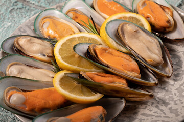Half seashells with mussel meat and lemon close-up.
