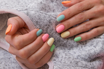 Colored matte manicure on female hands on a gray background