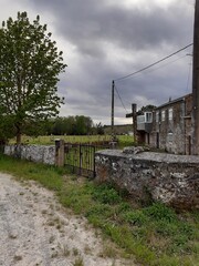 Pequeña cruz de piedra frente a una casa rural en Galicia © CDN
