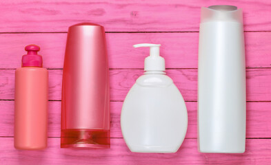 Bottles of shampoos on pink wooden background. Cosmetics. Top view