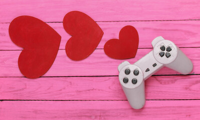 Game lover. Retro gamepad with red hearts on pink wooden background. Retro 80s. Top view.