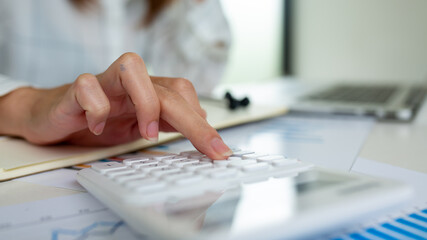 Business or accountant working on calculator to calculate business analyze data report and graph, accountancy document and laptop computer at office, Financial and Accounting concept.