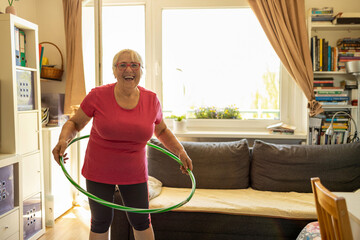 Older woman hula hooping at home
 - obrazy, fototapety, plakaty