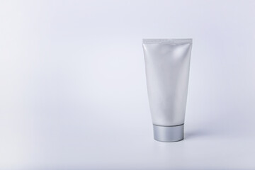 A tube of cream of silver color on a white background.