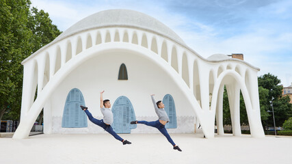 Two young twin brothers dancing contemporary ballet in the city with urban costume.