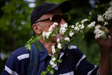 Latino american man sniffs a flowering branch in spring