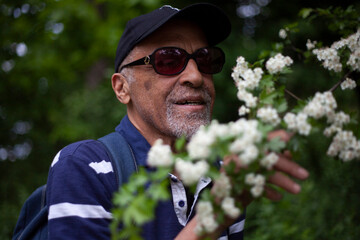 Latino American man in sunglasses likes a flowering branch in spring