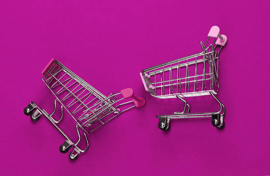 Two mini supermarket trolleys on blue background. Shopping concept.