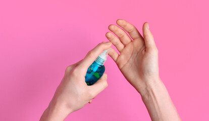 Hand disinfection with antiseptic on pink background