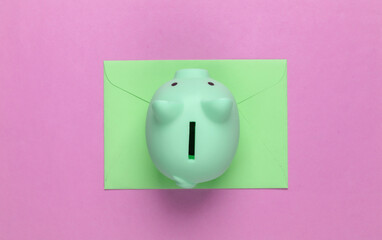 Piggy bank and envelope on pink background. Minimalistic studio shot. Overhead view. Flat lay.