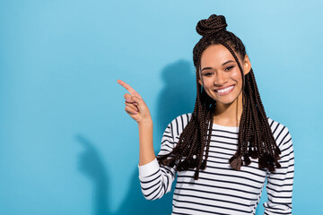 Photo portrait of smiling girl with dreadlocks showing empty space with finger smiling isolated pastel blue color background