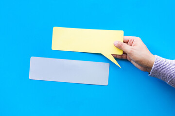 Person hand holding blank  bubbles speech paper in colorful background.