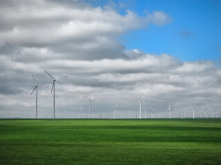 Eolian farm renewable energy in fresh green field against clear blue sky