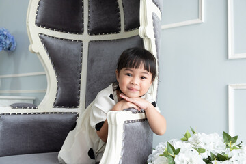 An asian toddler girl 4 years old sitting in a chair and rest her chin on hands