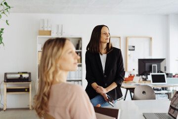 Fototapeta premium Two businesswoman sitting in a meeting looking to the side listening