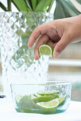 una persona exprime un limón de una pequeña jarra con limones cortados, fruta ácida