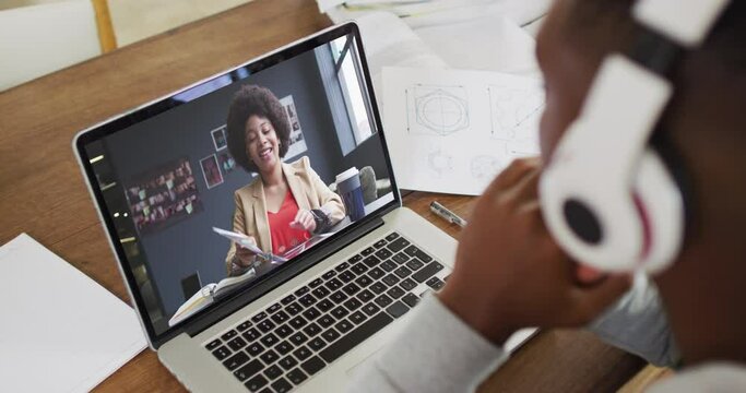 African american businessman sitting at desk using laptop having video call with female colleague
