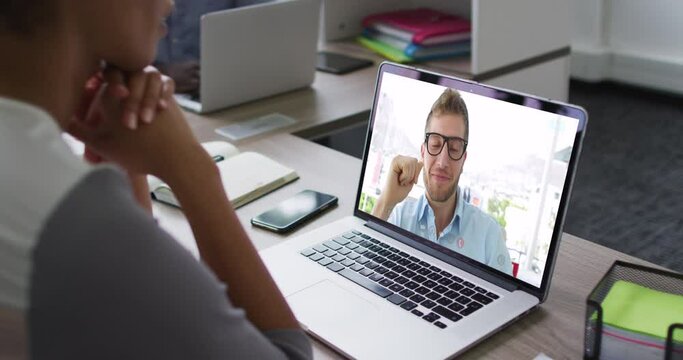 African american businesswoman sitting at desk using laptop having video call with male colleague