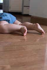 Baby wearing chambray shorts crawling; laminate wood flooring shows reflection of cute baby legs and toes