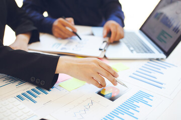 Business people use charts and graphs showing the results of successful teamwork in the office. Using graph sheets and notebook to work