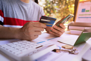 Young Man holding credit card and using mobile smartphone to Online shopping, e-commerce, internet banking, spending money. Concept of Shopping service on The online web and offers home delivery.