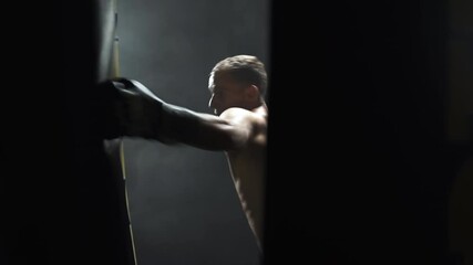 Professional kickboxer training with a boxing bag in a dark gym,smoke. - Powered by Adobe