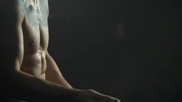 Closeup of a bodybuilder rubbing hands with chalk before workout,dark.