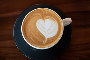 Cup of hot latte art coffee on wooden table