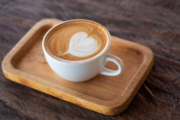 Cup of hot latte art coffee on wooden table